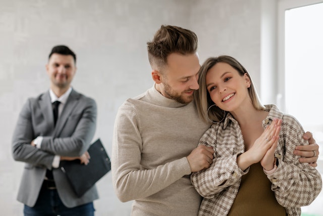 property manager standing behind smiling prospective tenants viewing property